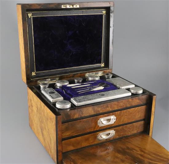 A Victorian burr walnut two drawer travelling toilet box containing ten silver mounted jars or bottles, by William Neal,